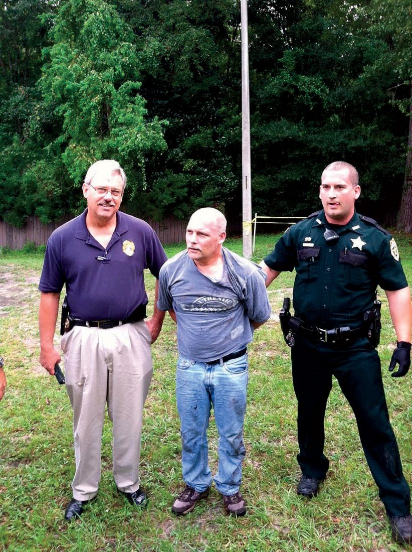 Detective William Royster of the Aiken, South Carolina, Police Department (left) and a Nassau Country Police officer apprehend Nordahl on August 26, 2013, at 10:01 a.m. in Hilliard, Florida.