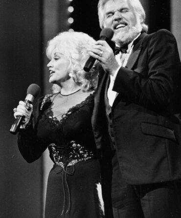 Dolly Parton and Kenny Rogers on stage singing into microphones