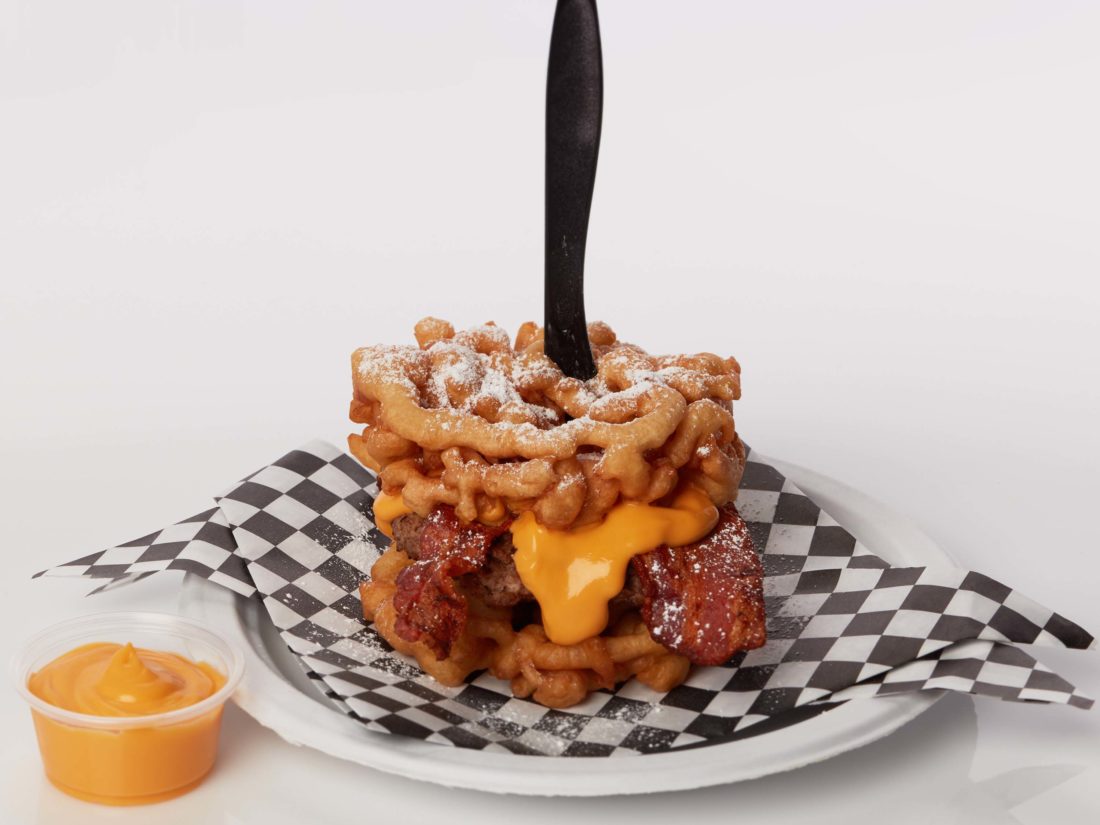 Funnel Cake Bacon Queso Burger
This hearty creation sandwiches a grilled burger patty, queso, and bacon between two funnel cake buns.