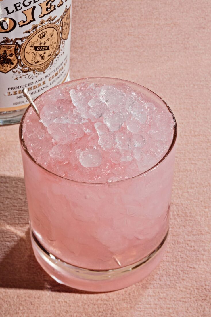 A pink drink in a low ball glass with crushed ice.