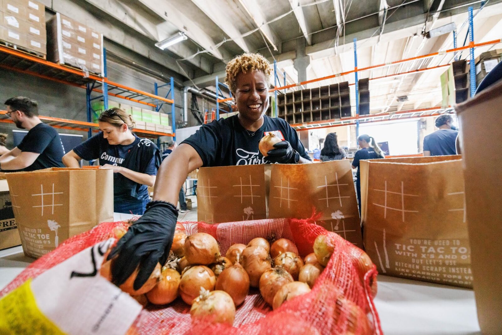 A woman reaches into a box of apples