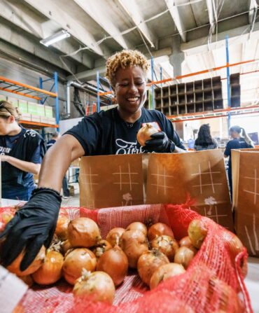 A woman reaches into a box of apples