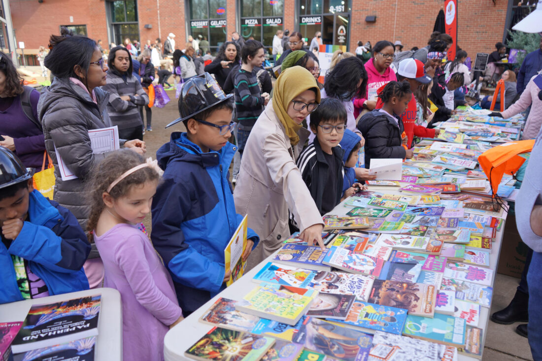 Kids and parents crowd around a table with books