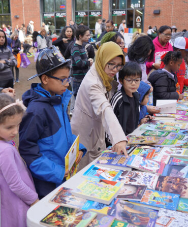 Kids and parents crowd around a table with books