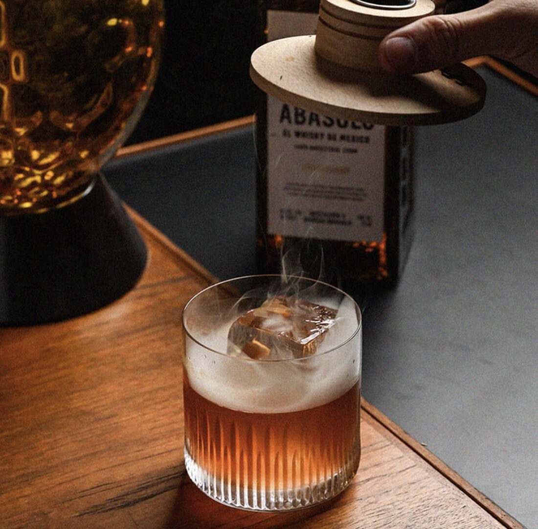 ANCESTRAL OLD FASHIONED Abasolo corn whiskey tepache syrup orange and mole bitters palo santo smoke credit The Cocktail Shaker Co