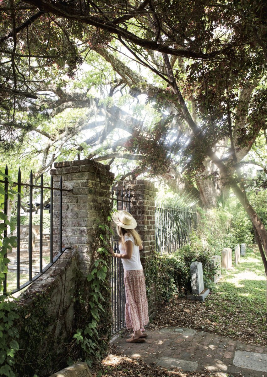 A woman peers through a garden gate