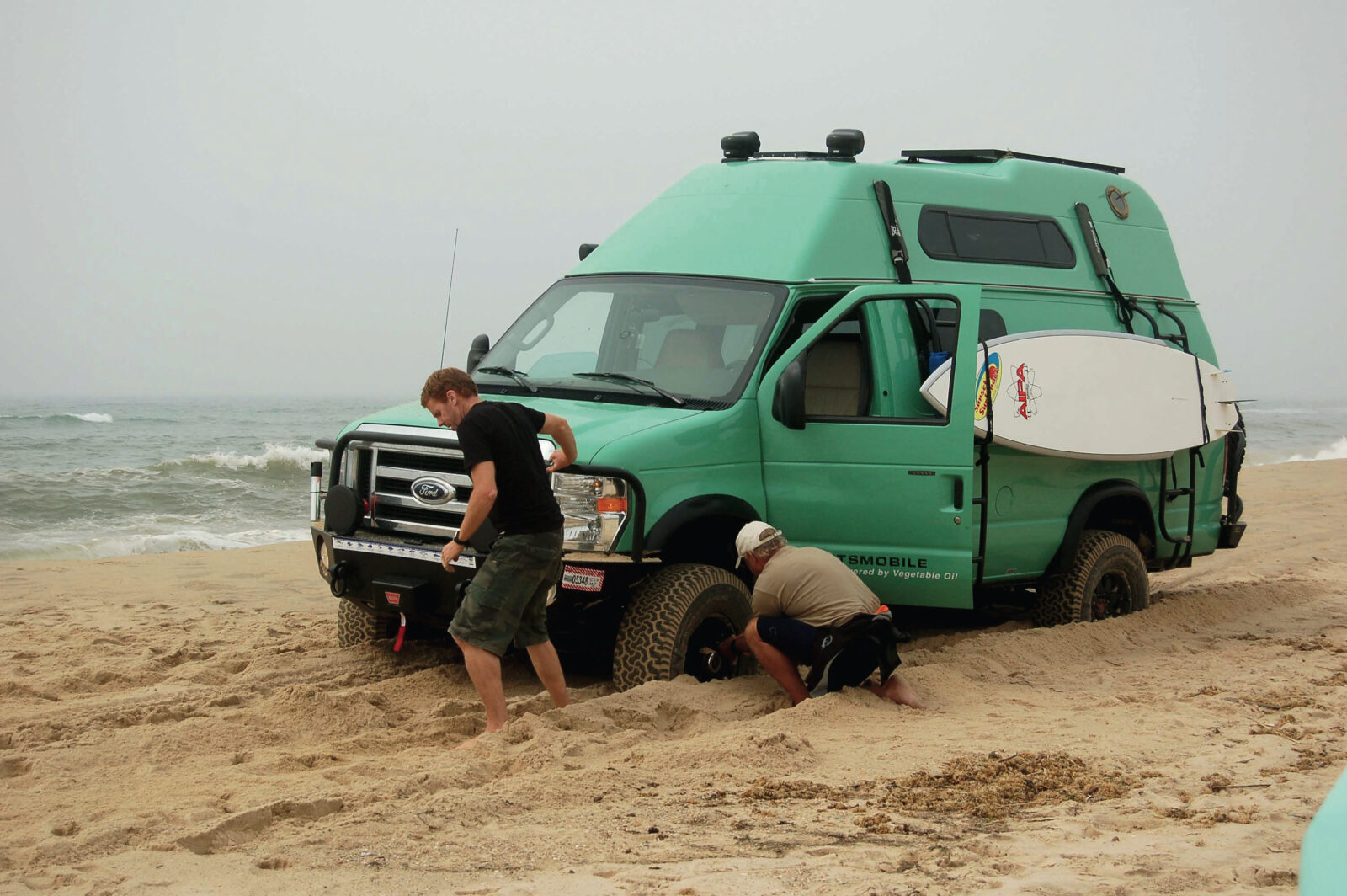 Two men dig a van out of sand