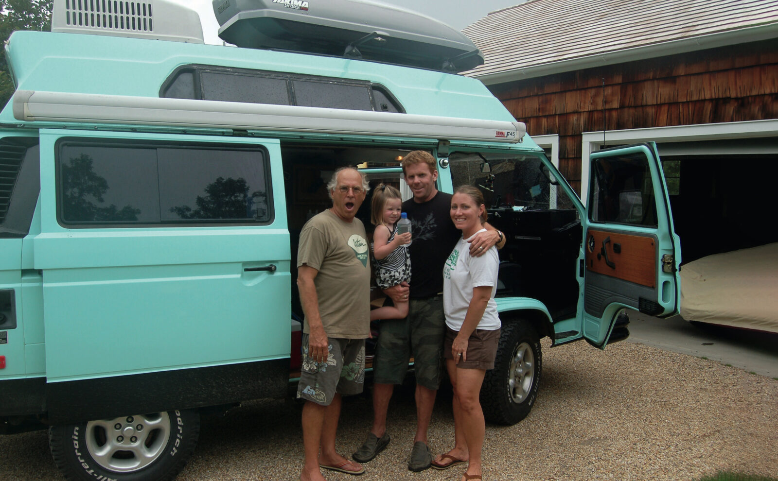 A group of people stand in front of a blue van