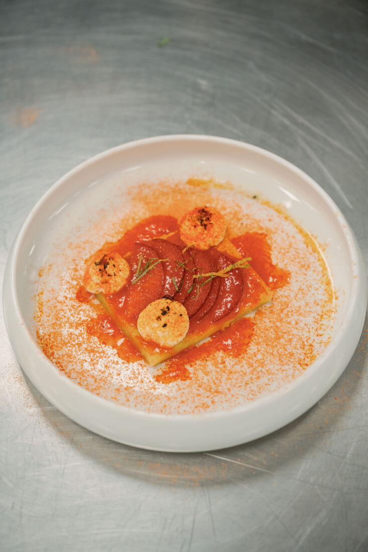 Plums in syrup with mochi butter cake, honey whipped cream, black sesame, and Li hing mui powder.