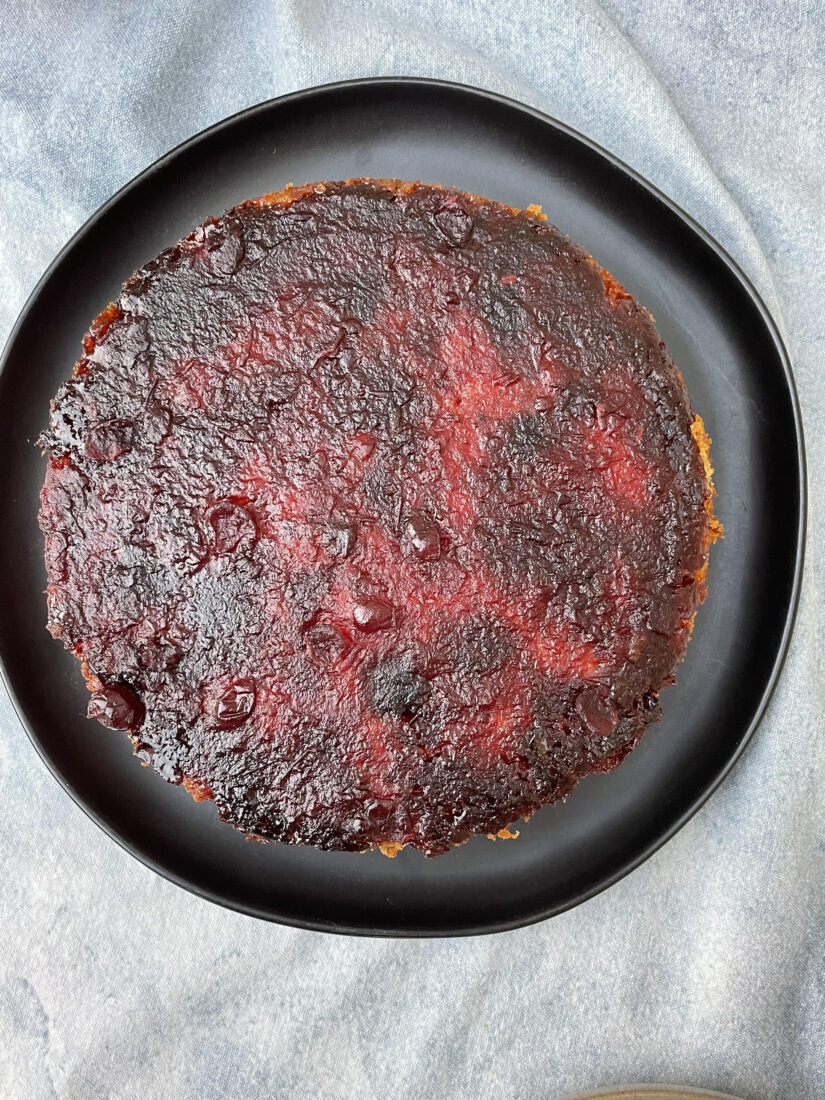 A round red cake on a black plate, seen from above