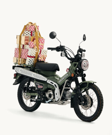 A green motor bike with wrapped Christmas presents topped on the back