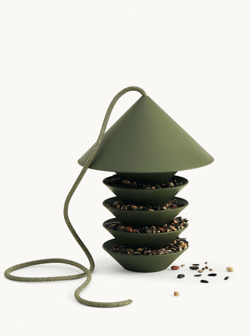 A green bird feeder with three tiers, filled with bird seeds