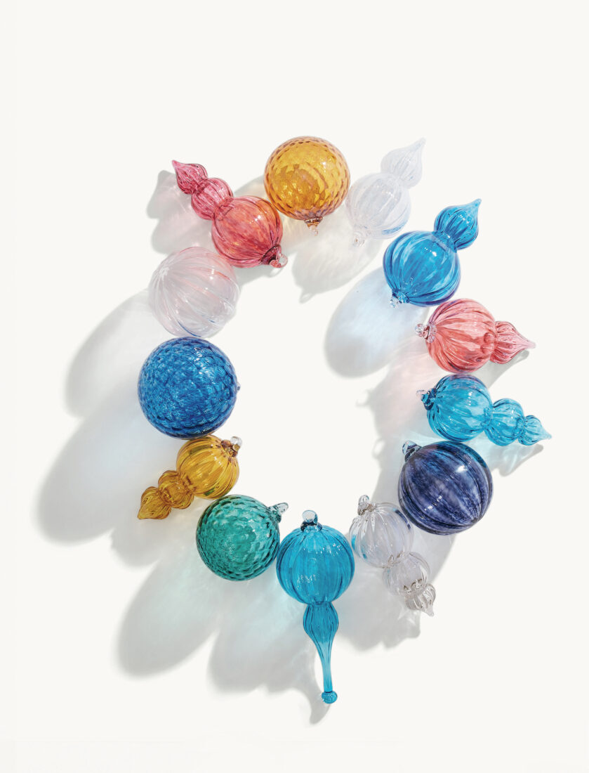 A bright and colorful assortment of bulbous and pointed glass ornaments are arranged in a ring