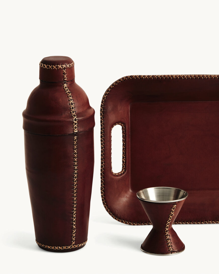 A cocktail shaker, jigger, and tray wrapped in fitted brown leather
