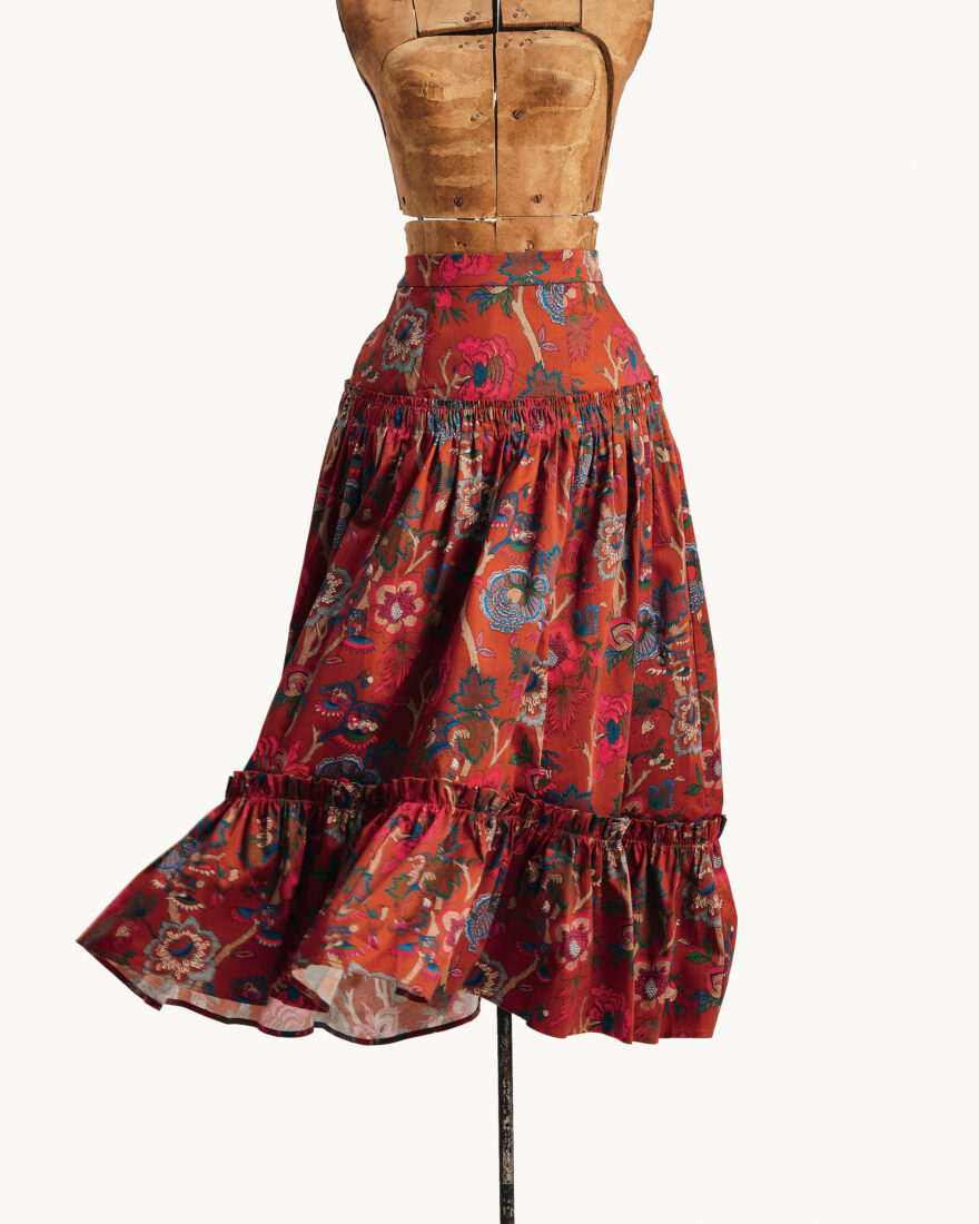 A shiny and ornately-patterned red skirt on a wooden mannequin 