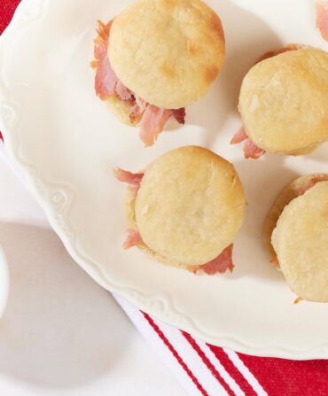 A plate of ham biscuits from above on a red and white stripe background