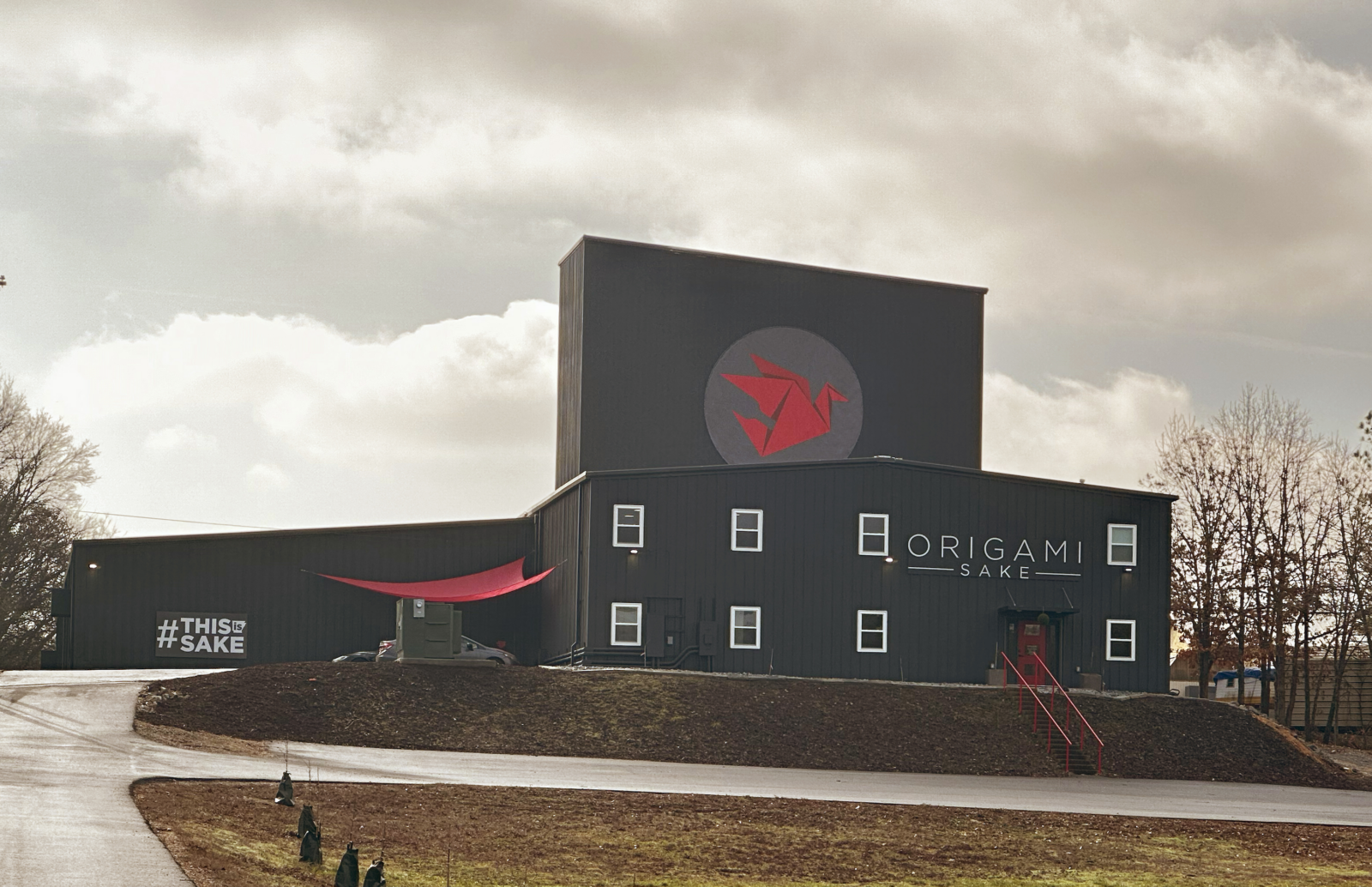 The outside of a sake distillery building; it is black and has red details