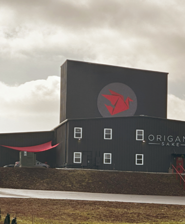 The outside of a sake distillery building; it is black and has red details