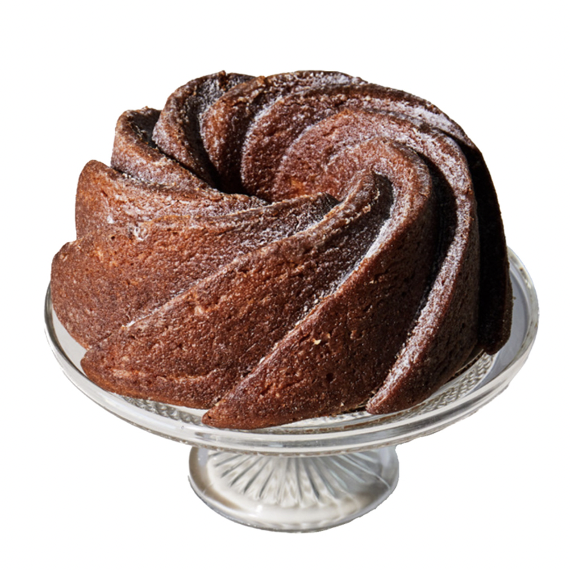 A brown bundt cake on a clear cake stand