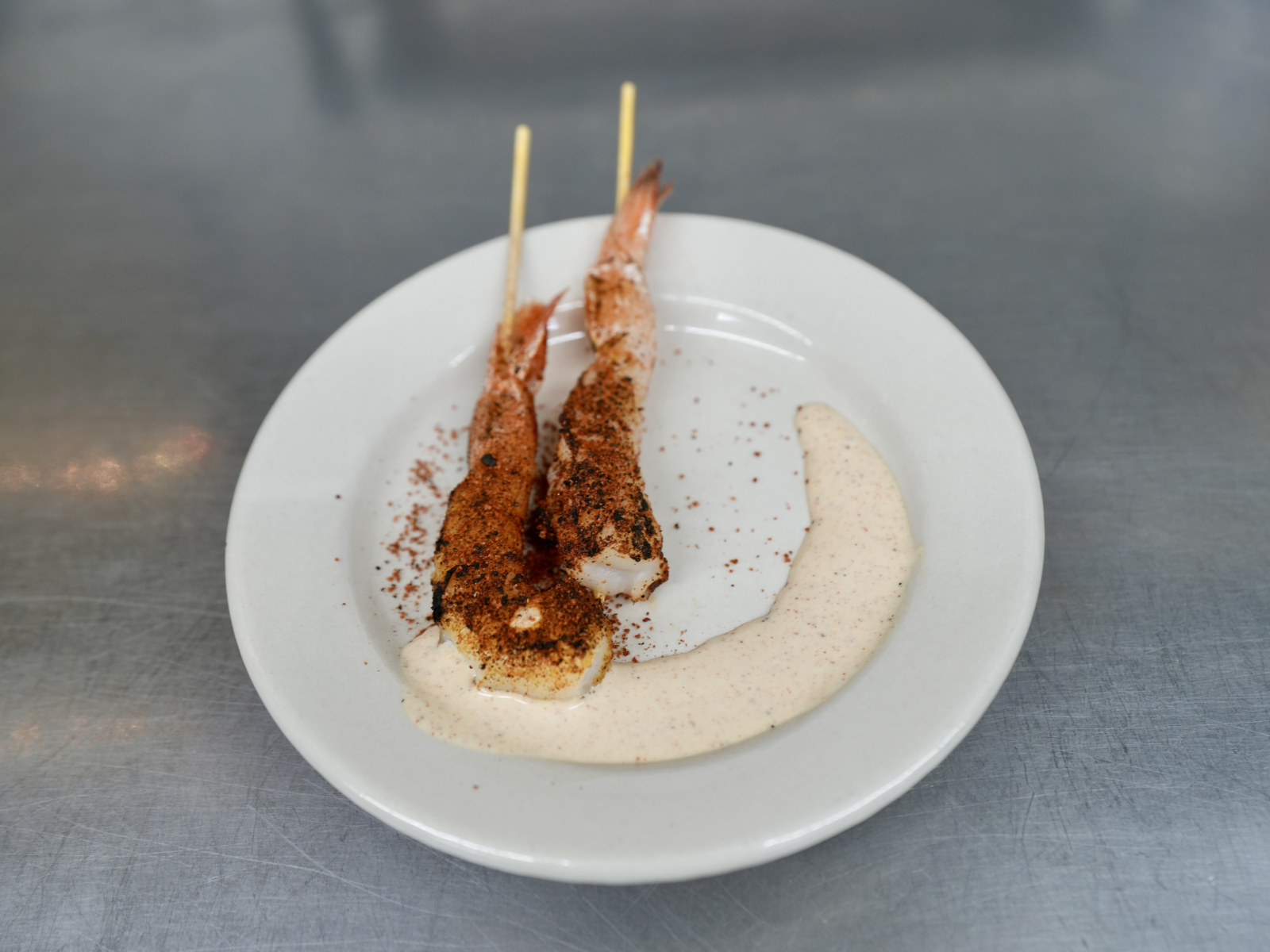 Two shrimp skewers on a white round plate.