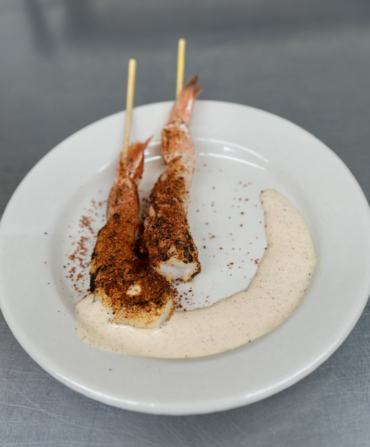 Two shrimp skewers on a white round plate.
