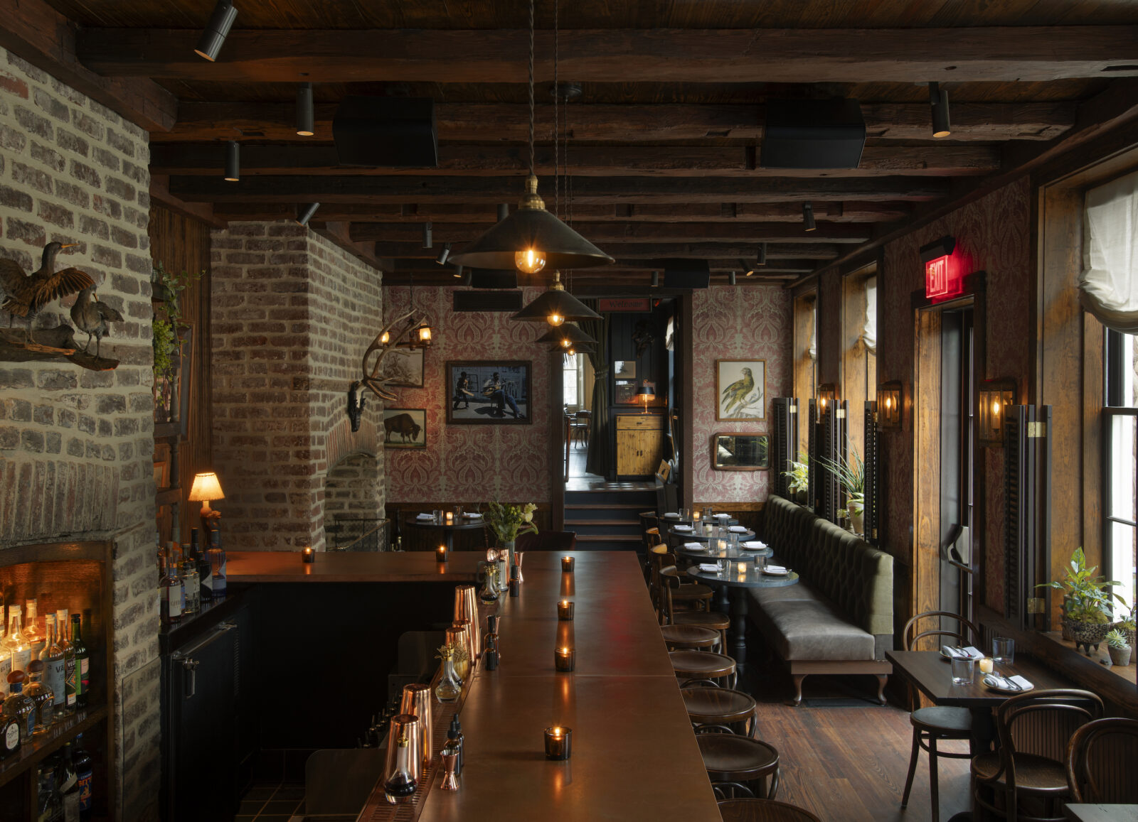 A long, cozy dining room with exposed beam ceilings and brick walls