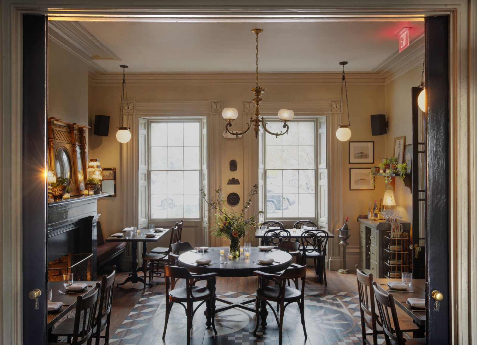 A parlor room with yellow walls, pendant lights, a set table, and a pattern painted on the wood floor