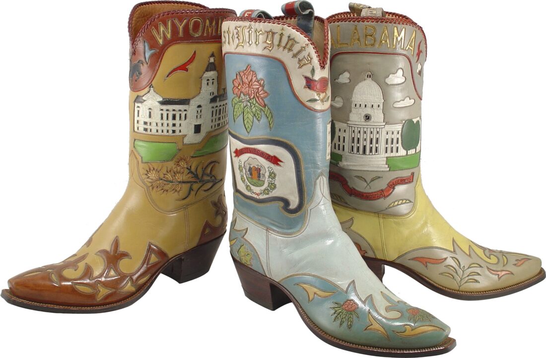 Three boots are laid of from the state collection: Wyoming (a brown boot with darker red details and the state capitol building), West Virginia (a blue boot with a pink flower, cardinal, and berries), and Alabama (a yellow and grey boot with the capitol building).