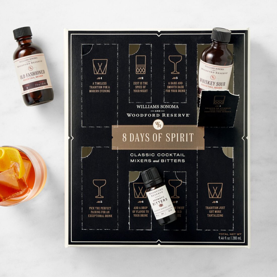 A black box with brown detailing, a whiskey sour bottle pops out of one panel and a bottle of aromatic bitters lays on one of the four bottom panels. An orange drink and old-fashioned mixer bottle lay to the left