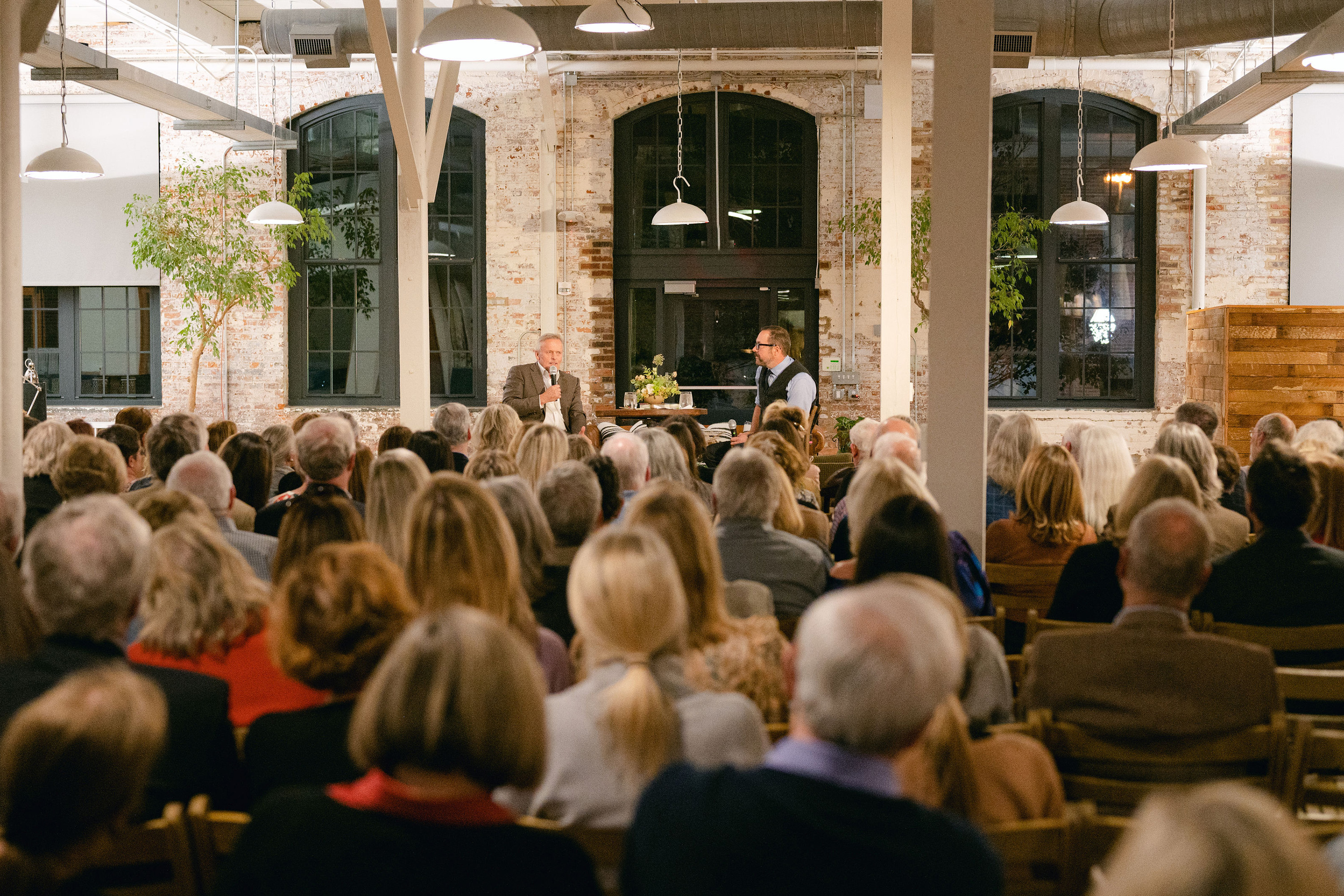 A crowd watches John Grisham and Jonathan Miles seated on a stage