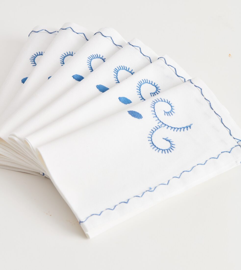 A stack of white napkins with blue stitching