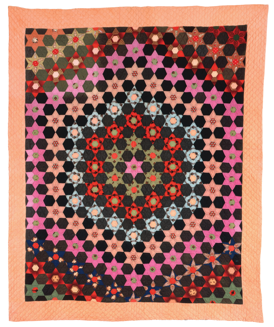 A hexagon-patterned quilt with black, pink, red, green, and light blue fabric on a lighter orange border.
