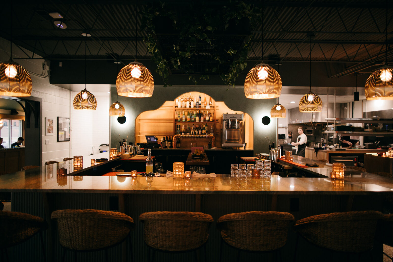 A copper-topped bar with seats and an arch-shaped shelf for bottles