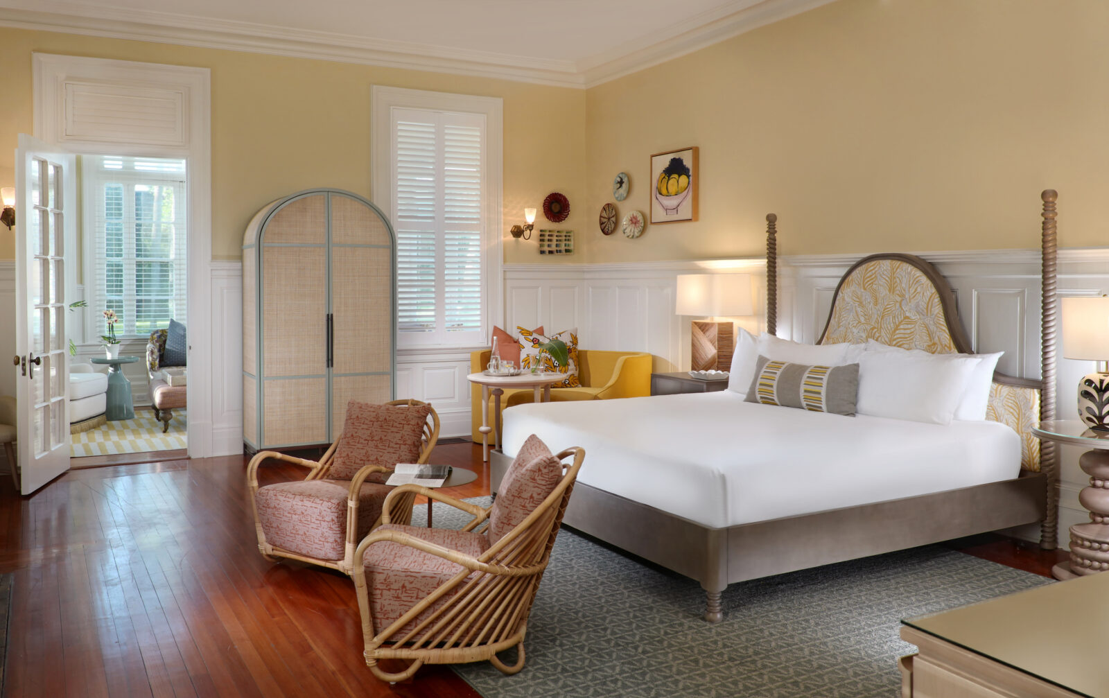 A room with wood floors, a curved closet, rattan chairs, and a yellow seat