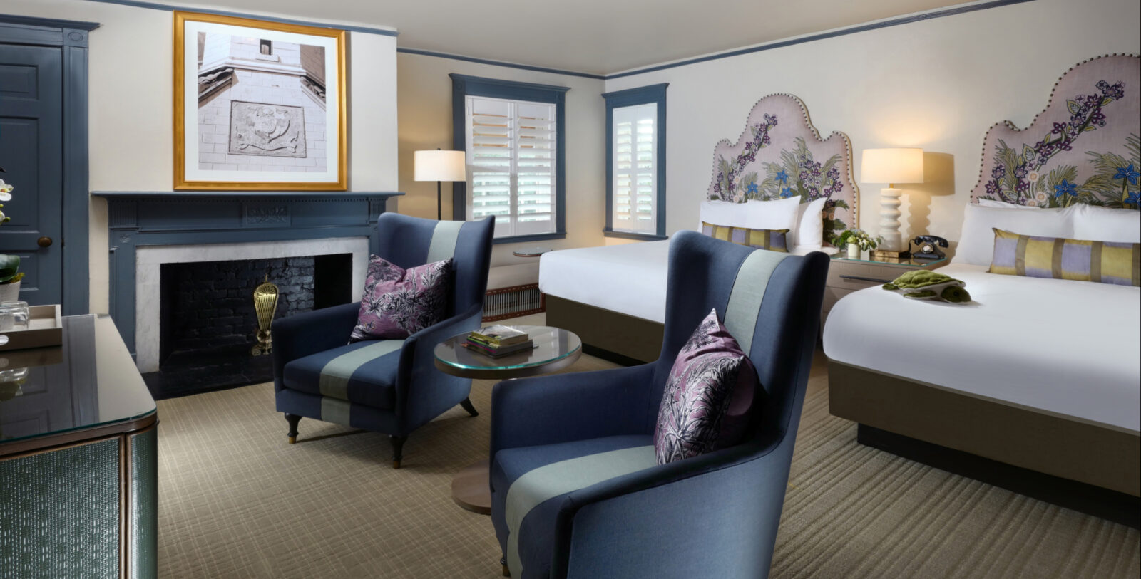 A room with navy chairs, window trim, and a fireplace