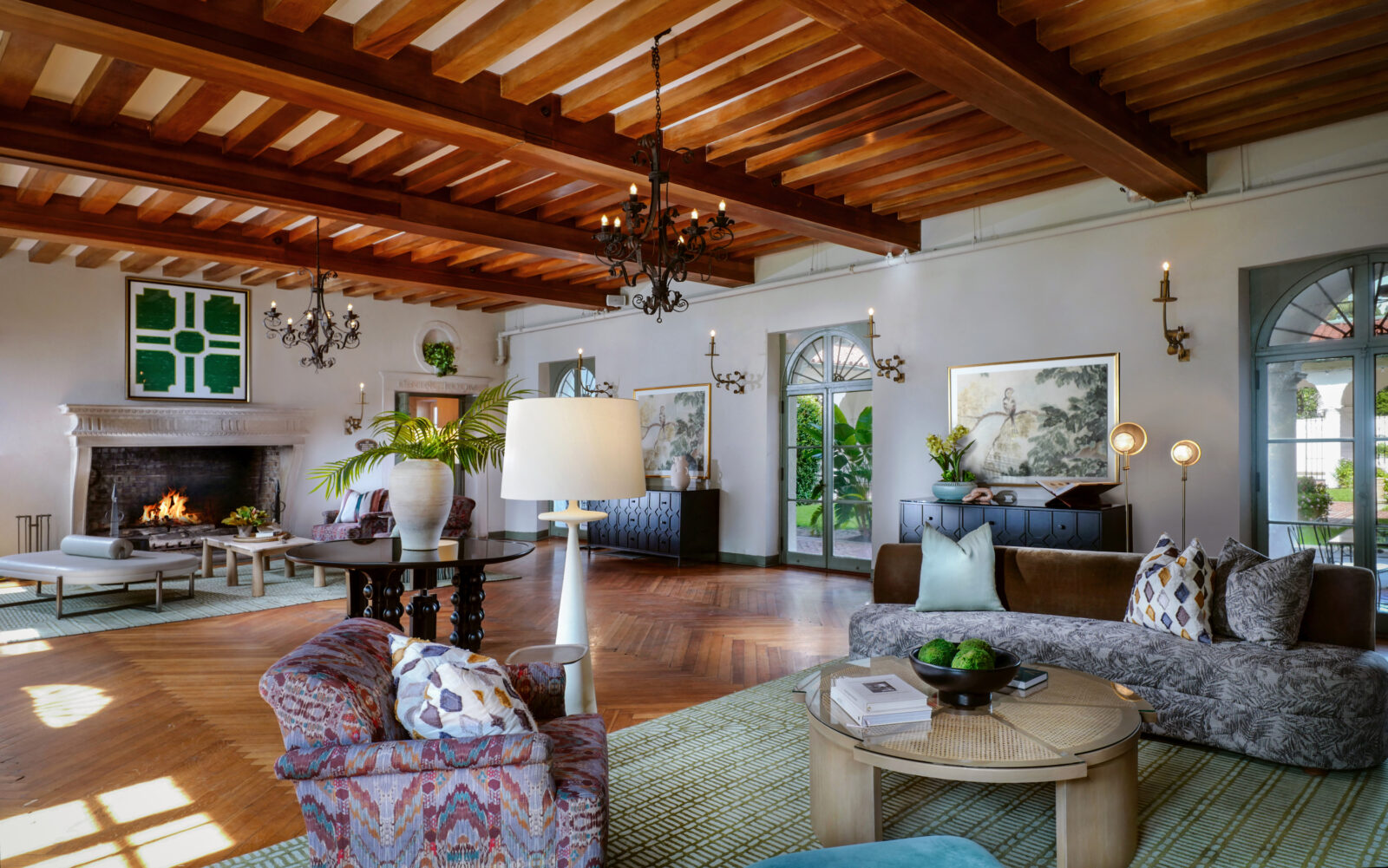 A light-filled cottage with wood beams, a fireplace, and printed furniture