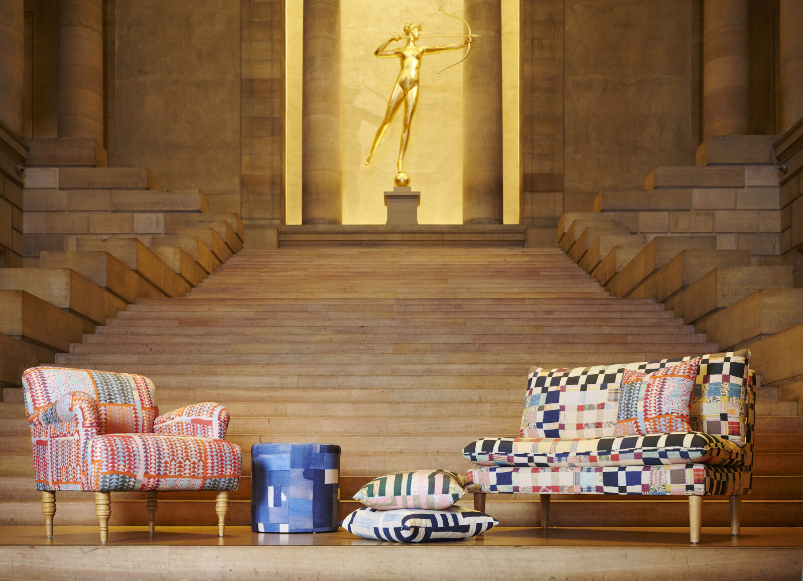 Furniture with quilted patterns sit at the foot of a staircase