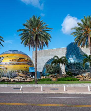 The outside of a museum with a large painted orb and a sculptural glass element