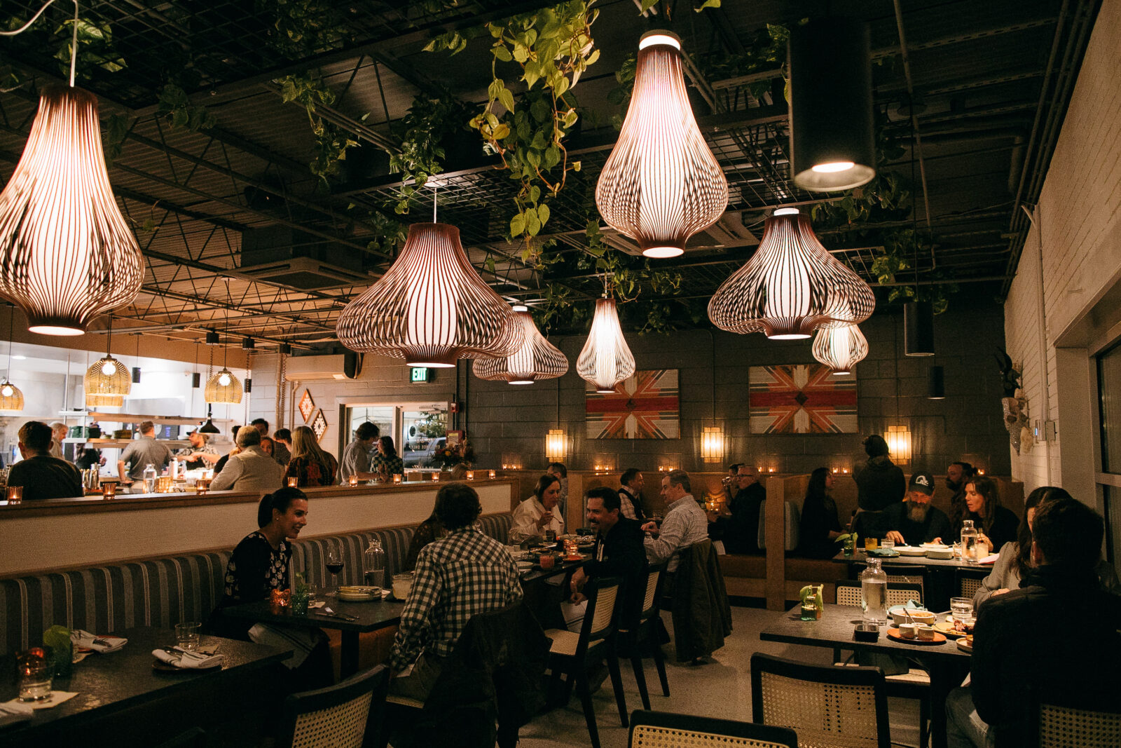 Diners in a dining room with plants on the ceiling and pear-shaped fixtures