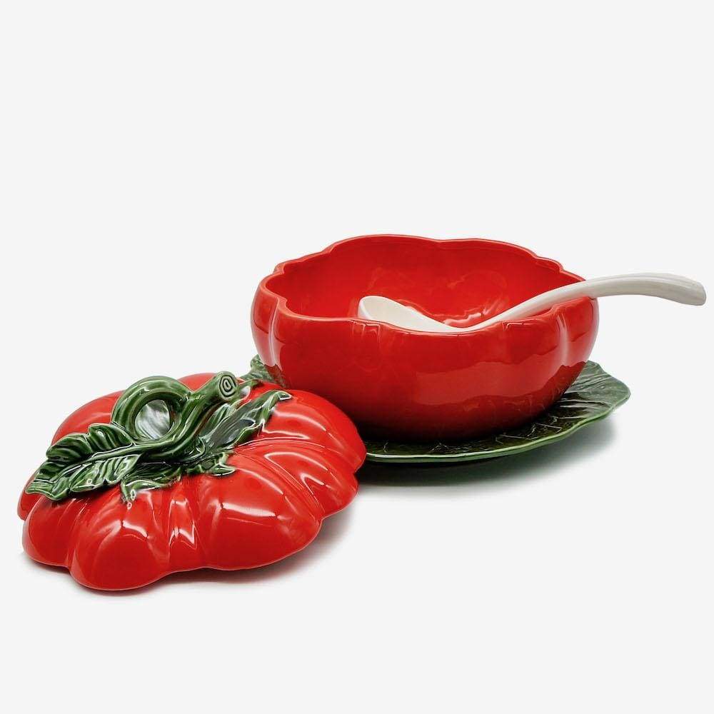 A bowl that looks like a tomato with a white ladle