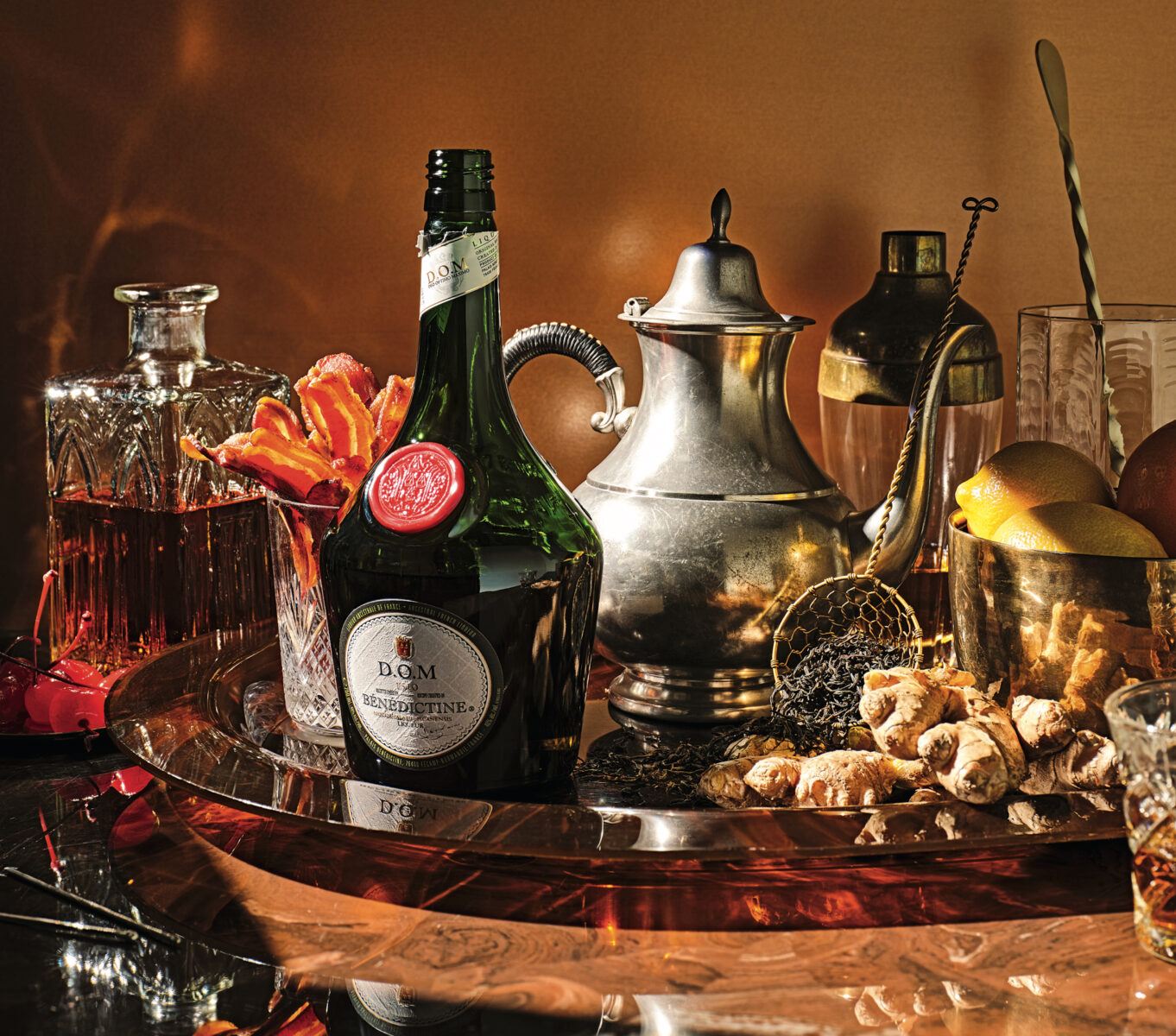 A bar cart spread of bourbon, Benedictine, ginger, tea, and bacon