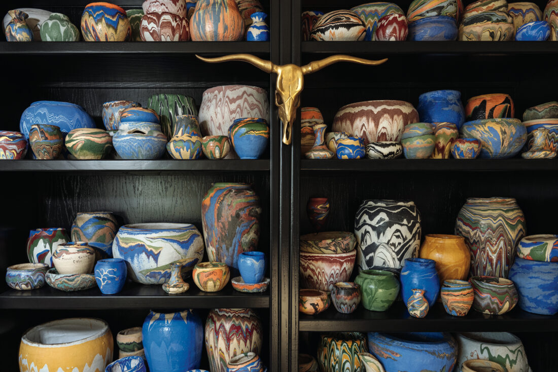Mathis’s 150-vessel-strong Ozark Roadside Tourist Pottery collection in his Oklahoma City living room. The vessels have swirling, colorful patterns.