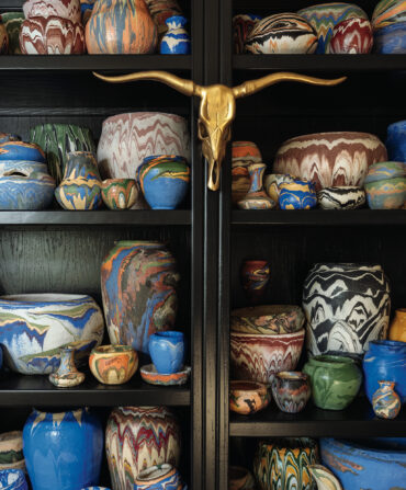 Mathis’s 150-vessel-strong Ozark Roadside Tourist Pottery collection in his Oklahoma City living room. The vessels have swirling, colorful patterns.