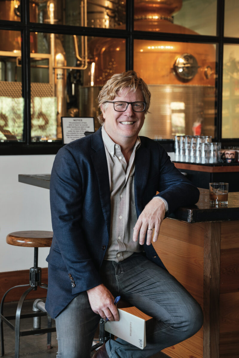 A man wearing a navy suit sits at a bar