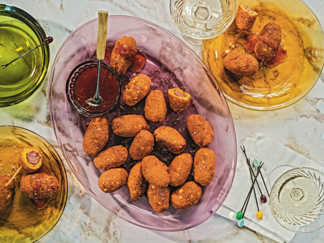 A tablescape of colorful glass plates with mini corn dogs and sauce for dipping, plus decorative toothpicks