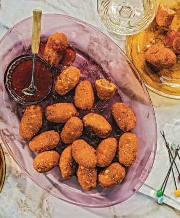 A tablescape of colorful glass plates with mini corn dogs and sauce for dipping, plus decorative toothpicks