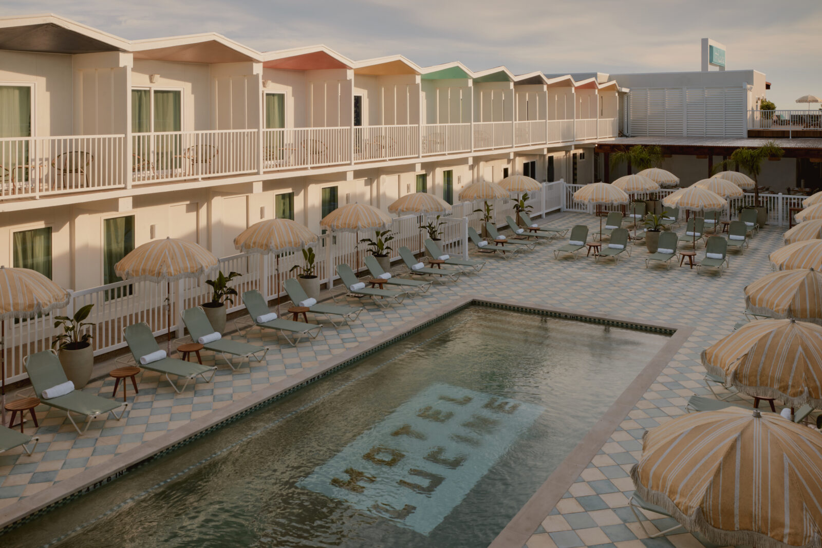 Taken from the second-floor balcony, looking down at the pool at the Hotel Lucine surrounded by lounge chairs and umbrellas.
