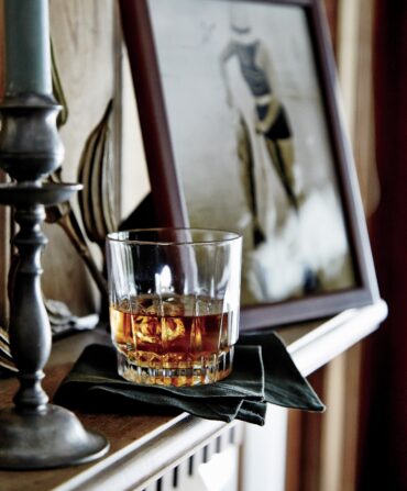 A glass of bourbon on a shelf