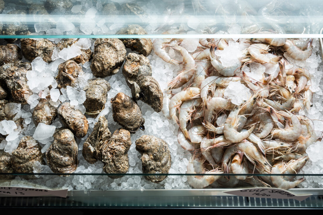A display of fresh shrimp and oysters over ice.