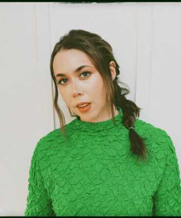 A portrait of a woman wearing a green sweater with her hair in a braid